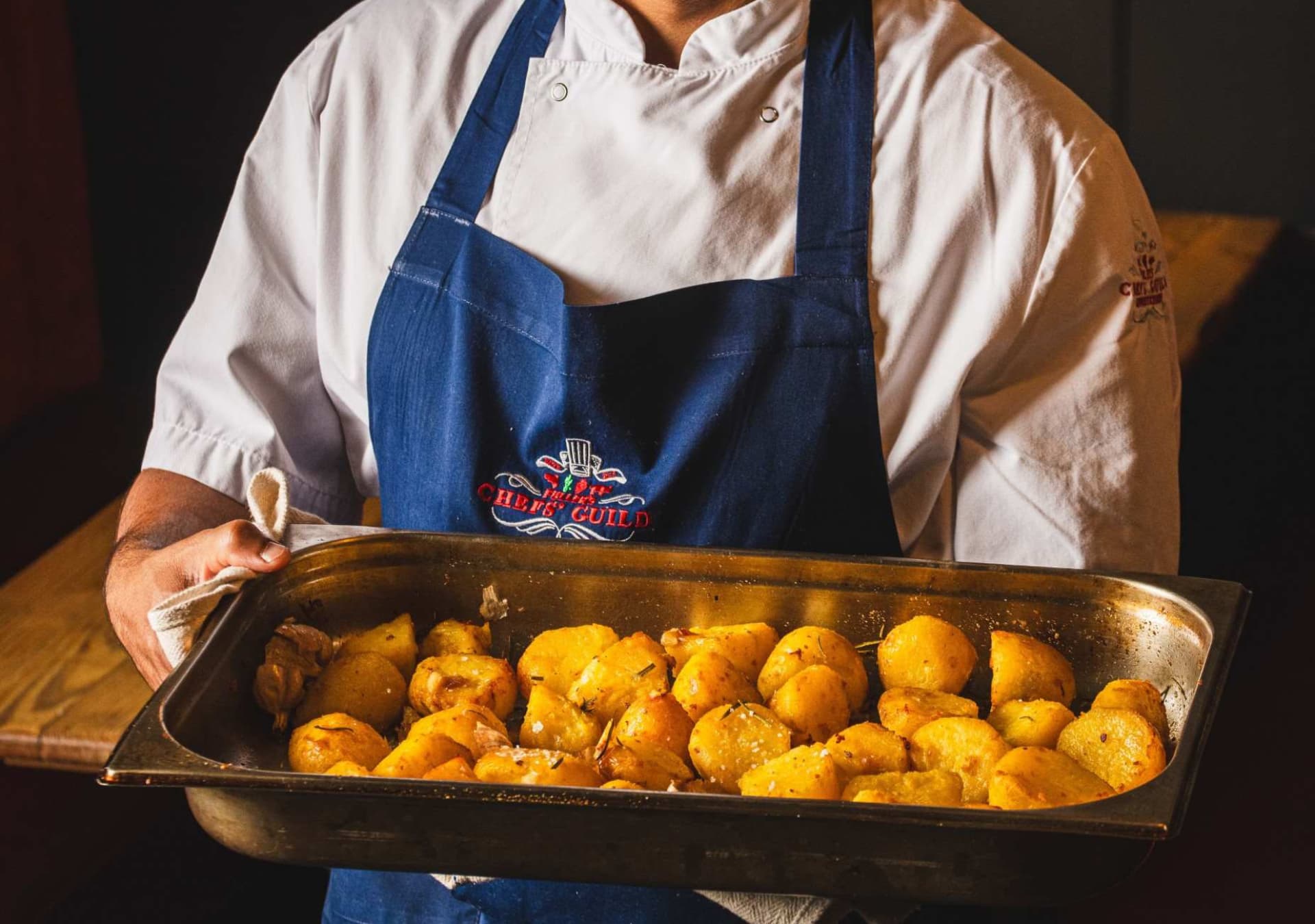 Chef holding tray of roast potatoes